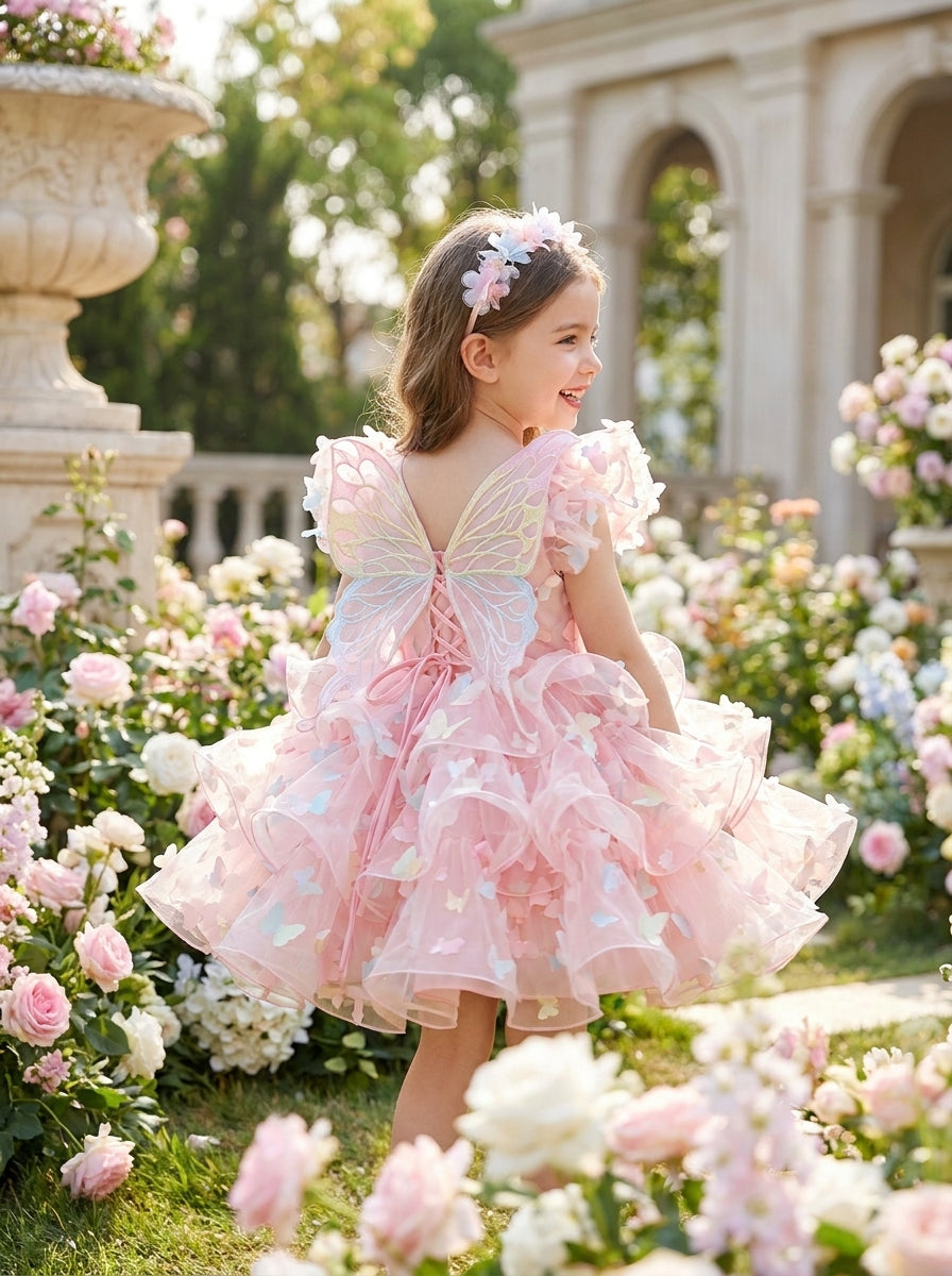 Back view of a child wearing a pink dress with pastel butterfly wings, a lace-up back and a tiered ruffle skirt.