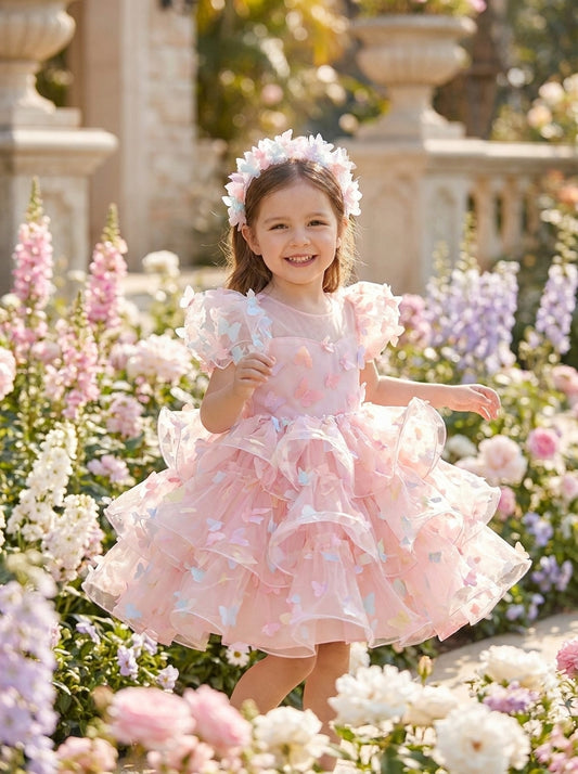 Front view of a child wearing a pink dress with ruffled short sleeves, pastel butterfly appliqués and a tiered ruffle skirt.