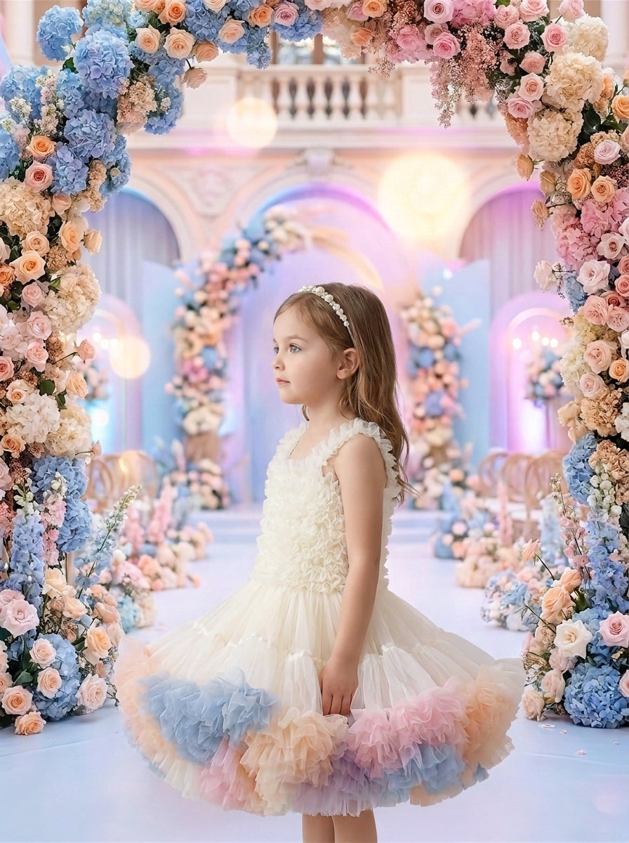 Side view of a child wearing a cream dress with a ruffled bodice and pink, peach and blue skirt panels.